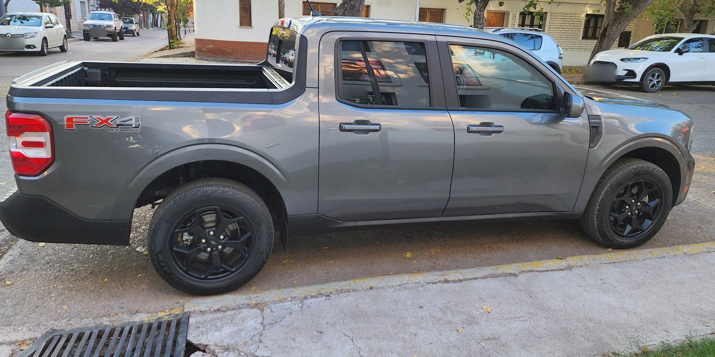 Ford Maverick gris estacionada en la calle, fotografiada de perfil. Las patentes están difuminadas.